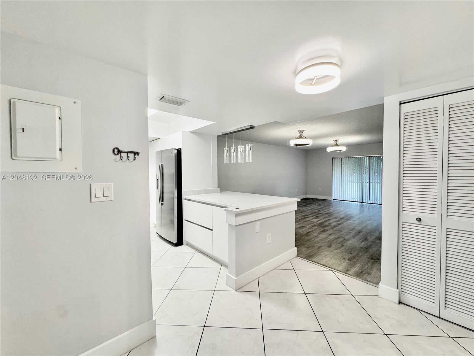 A kitchen with white cabinets and a breakfast bar opens into a living area — 8600 NW 34th Pl # B102, Sunrise FL 33351, SUNRISE, FL