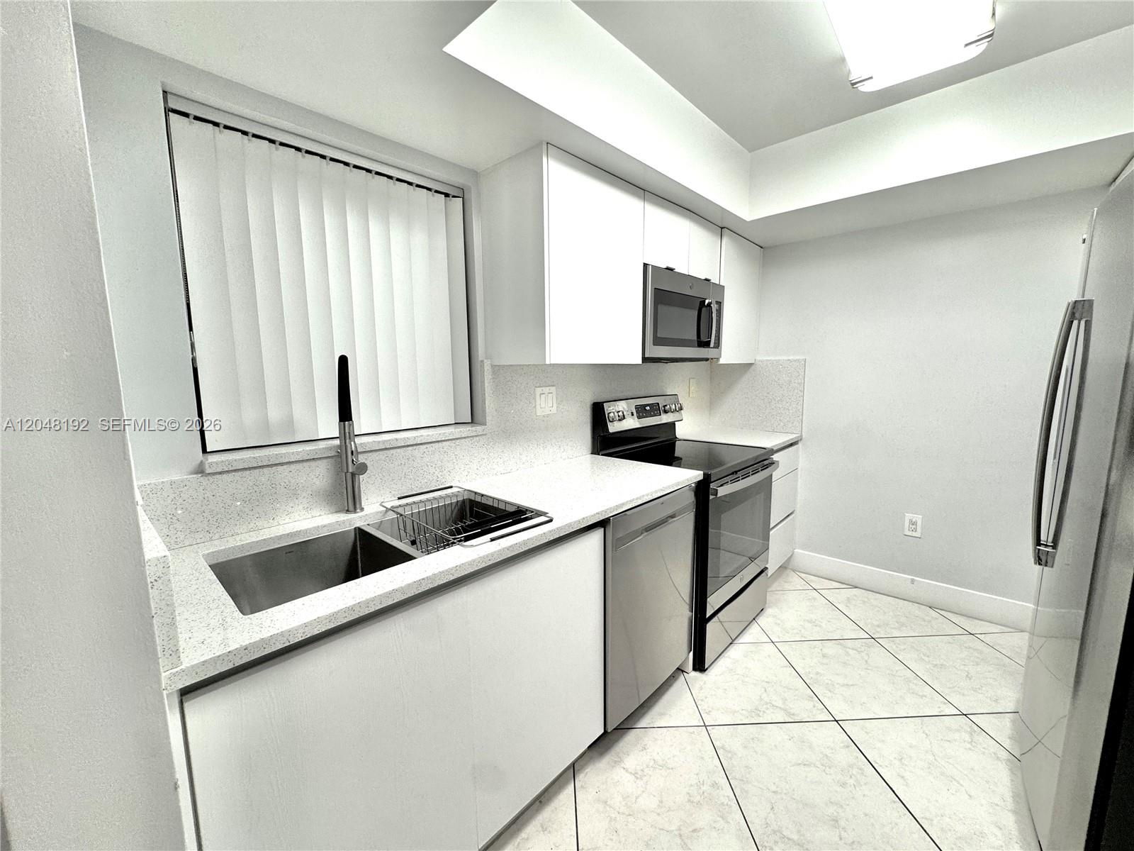 A modern kitchen features white cabinets, stainless steel appliances, and light-colored countertops — 8600 NW 34th Pl # B102, Sunrise FL 33351, SUNRISE, FL