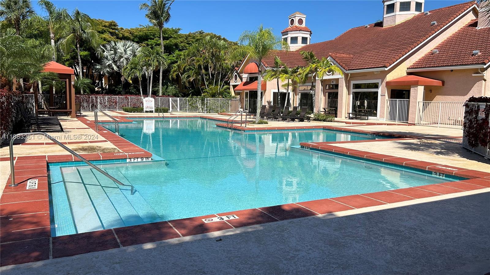 An outdoor swimming pool with a shallow entry area sits beside a residential clubhouse building — 15551 SW 104th Ter # 828, Miami FL 33196, MIAMI, FL
