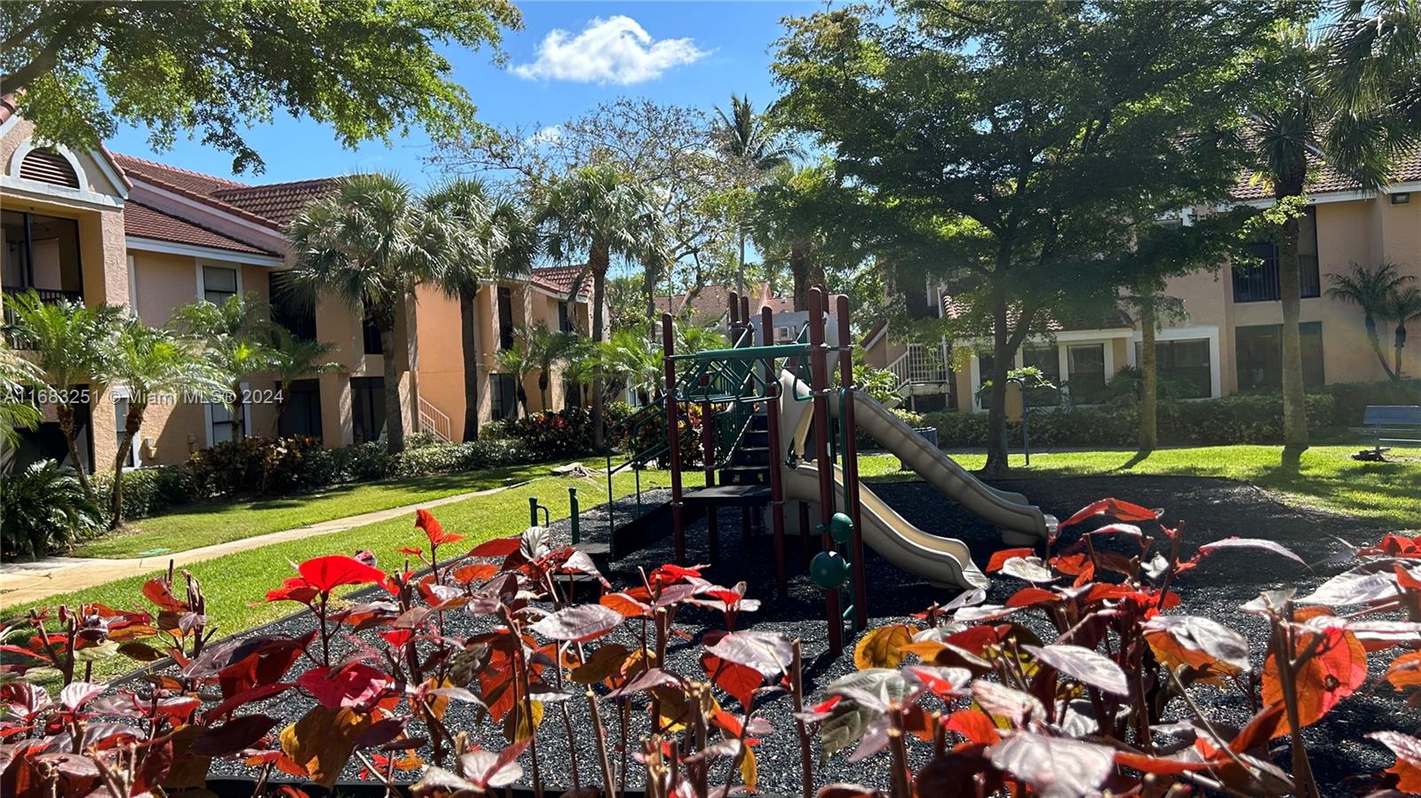A playground with a slide sits in a grassy courtyard between two-story apartment buildings — 15551 SW 104th Ter # 828, Miami FL 33196, MIAMI, FL