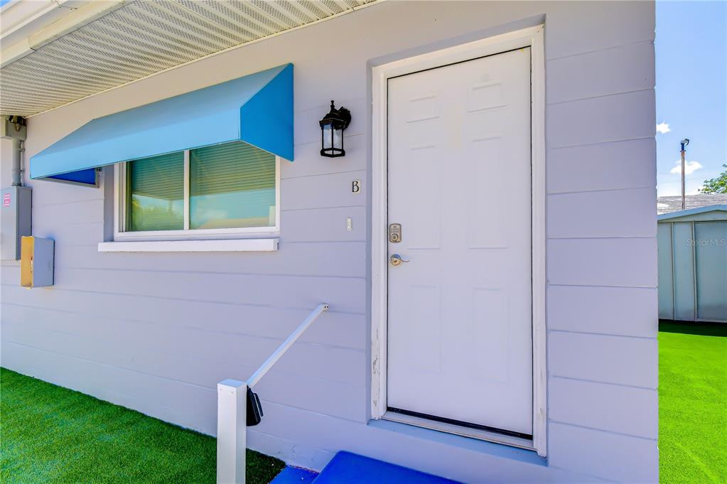 A light blue exterior wall features a white door labeled B and a window awning — 190 73RD AVENUE UNIT B, ST PETE BEACH, FL