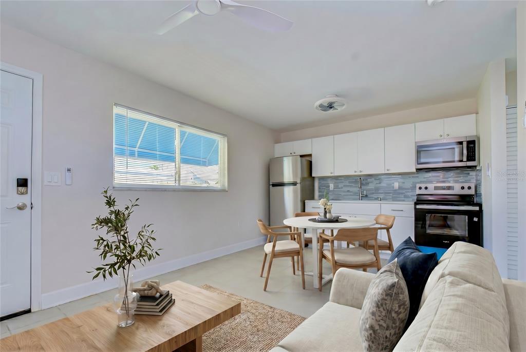 A kitchen and living area feature white cabinets, stainless steel appliances, and a dining table — 190 73RD AVENUE UNIT B, ST PETE BEACH, FL