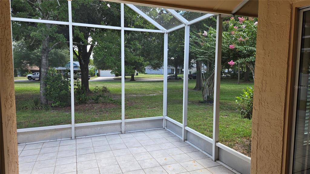 A screened-in patio with light-colored tile flooring overlooks a grassy yard with mature trees — 1657 TREMONT LANE, WINTER PARK, FL