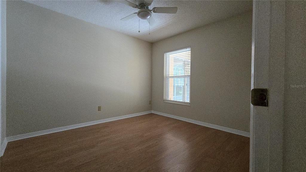 An empty bedroom features light-colored walls, wood-look flooring, a ceiling fan, and a single window — 1657 TREMONT LANE, WINTER PARK, FL
