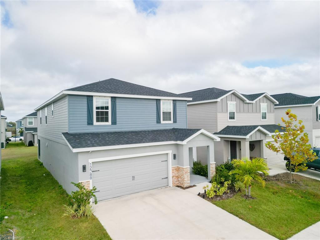 A two-story suburban house with a gray garage, blue siding, and a concrete driveway — 12288 CYPRESS BRANCH STREET, RIVERVIEW, FL