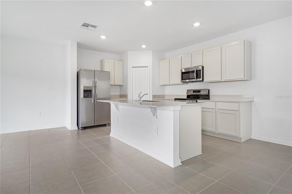 A kitchen with white cabinets, stainless steel appliances, a center island, and tiled flooring — 2728 LOOKOUT RIDGE ROAD, LAKE HAMILTON, FL