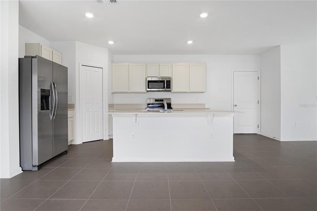 A kitchen with white cabinets, stainless steel appliances, a center island, and gray tile flooring — 2728 LOOKOUT RIDGE ROAD, LAKE HAMILTON, FL