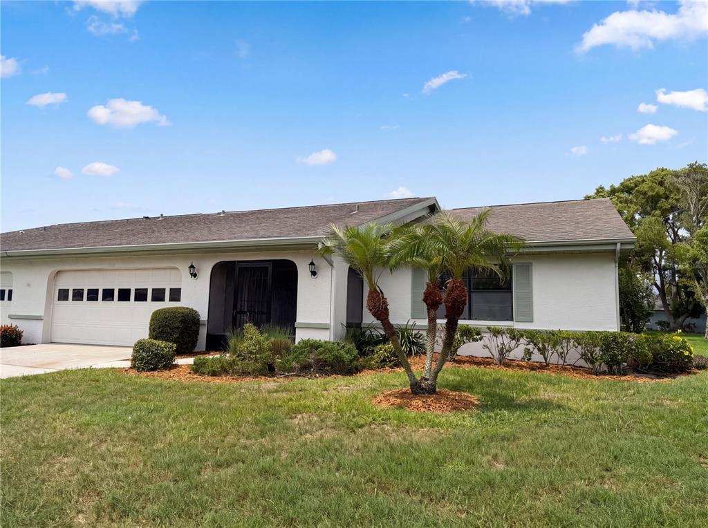 A single-story white house with a two-car garage and a palm tree in the yard — 1404 LELAND DRIVE UNIT 0, SUN CITY CENTER, FL