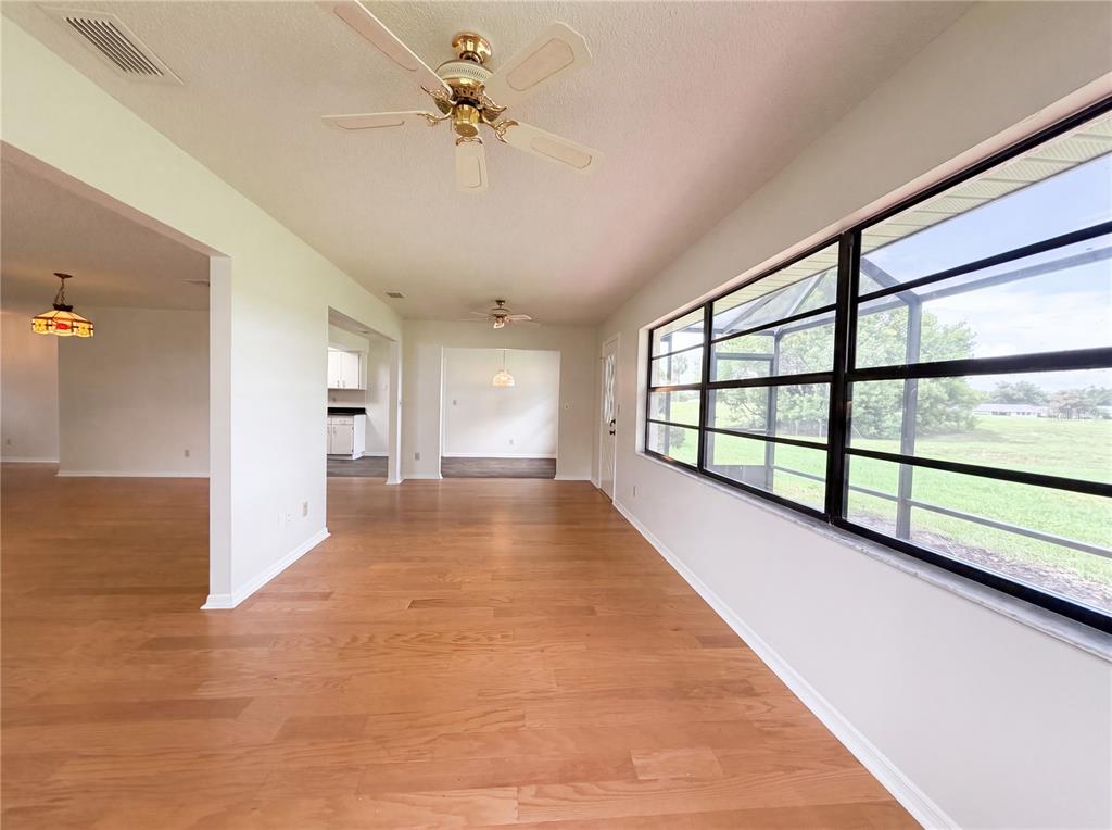 A sunroom with hardwood flooring, a ceiling fan, and large windows overlooking a grassy yard — 1404 LELAND DRIVE UNIT 0, SUN CITY CENTER, FL