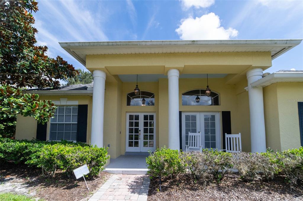 A yellow house exterior features a covered porch with white columns and double glass doors — 2960 ASHTON TERRACE, OVIEDO, FL