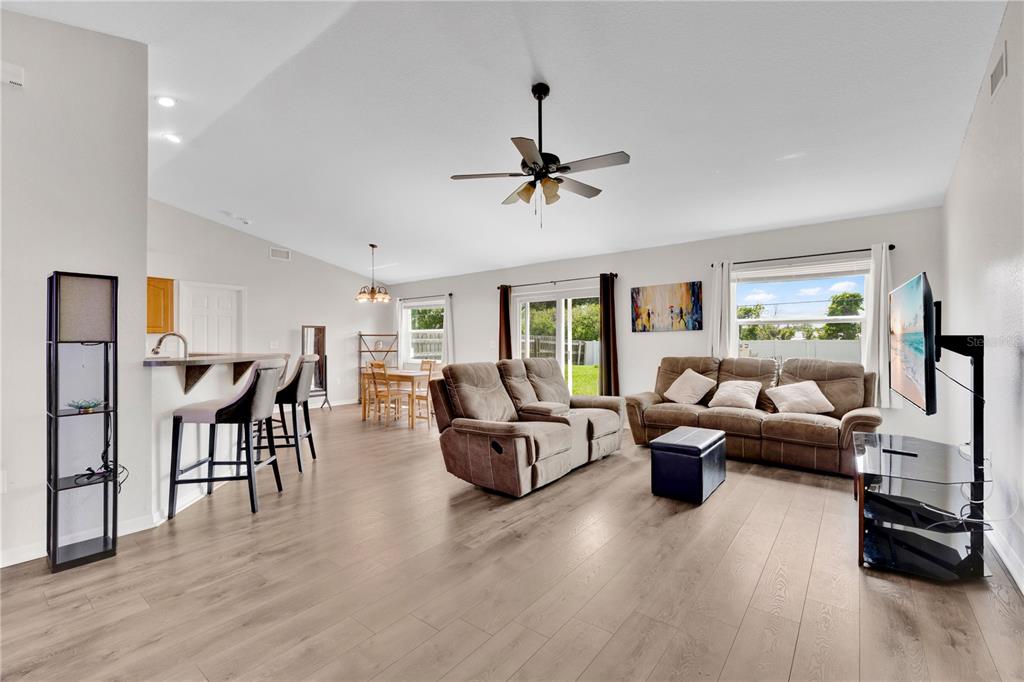A living room with wood-look flooring, a brown sofa, a recliner, and an open kitchen — 6315 HAMPTON POINTE CIRCLE, LAKELAND, FL