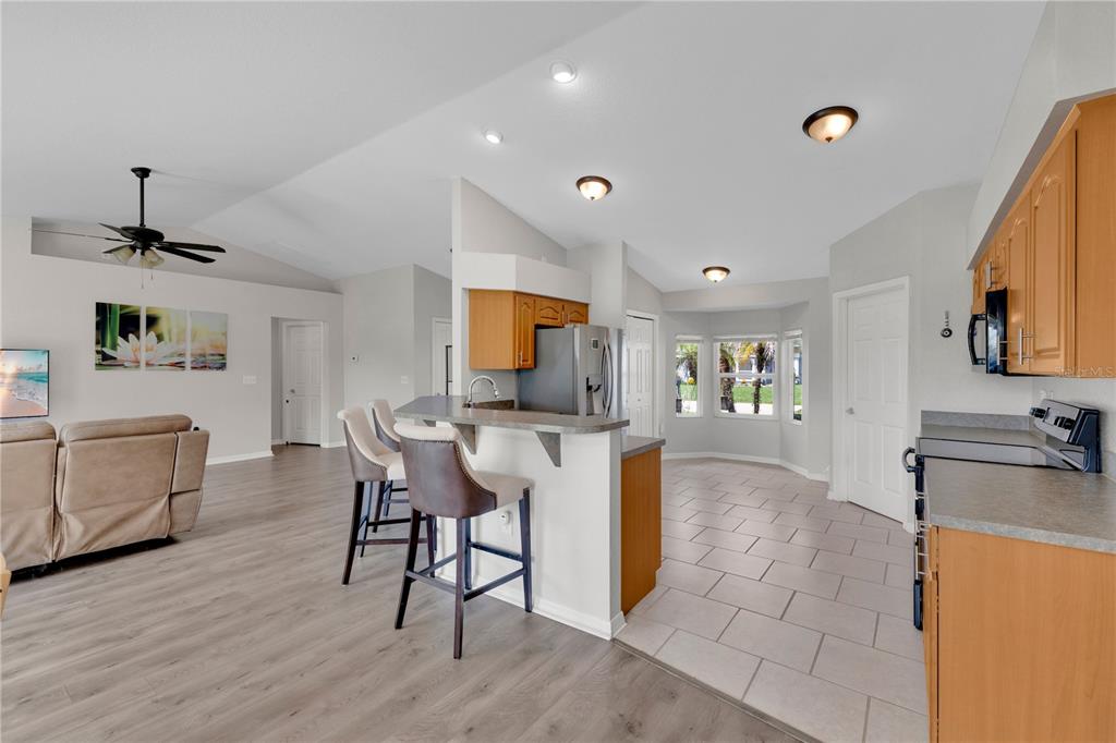 An open-concept kitchen with a breakfast bar, light wood cabinets, and tile flooring — 6315 HAMPTON POINTE CIRCLE, LAKELAND, FL