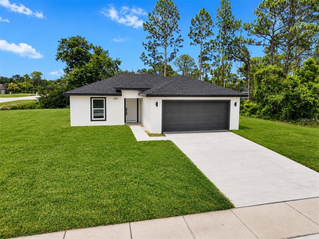 A single-story white house with a dark roof and a two-car garage — 608 COUGAR BOULEVARD, SEBRING, FL