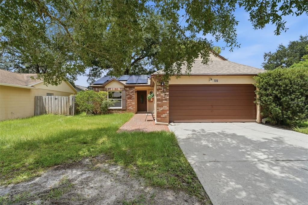 A single-story brick and stucco house with a two-car garage and solar panels on roof — 723 OAK MANOR CIRCLE, ORLANDO, FL