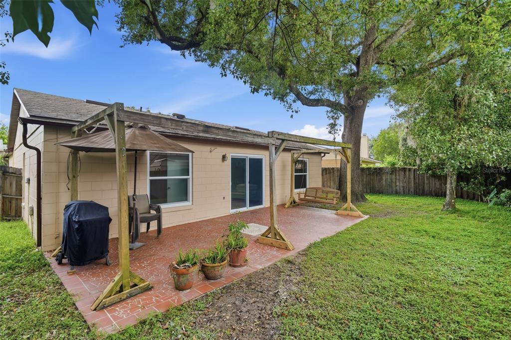 A backyard patio with a wooden pergola, a grill, a porch swing, and a large tree — 723 OAK MANOR CIRCLE, ORLANDO, FL