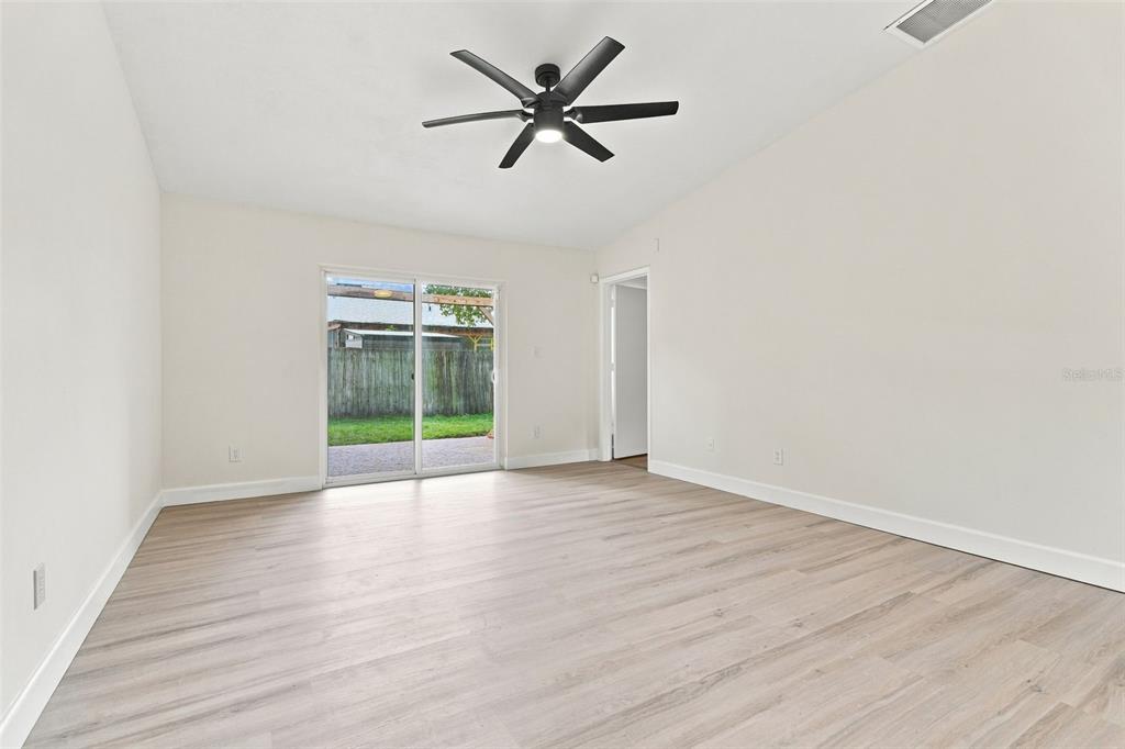 An empty room with light wood-look flooring, white walls, a ceiling fan, and sliding glass doors — 723 OAK MANOR CIRCLE, ORLANDO, FL