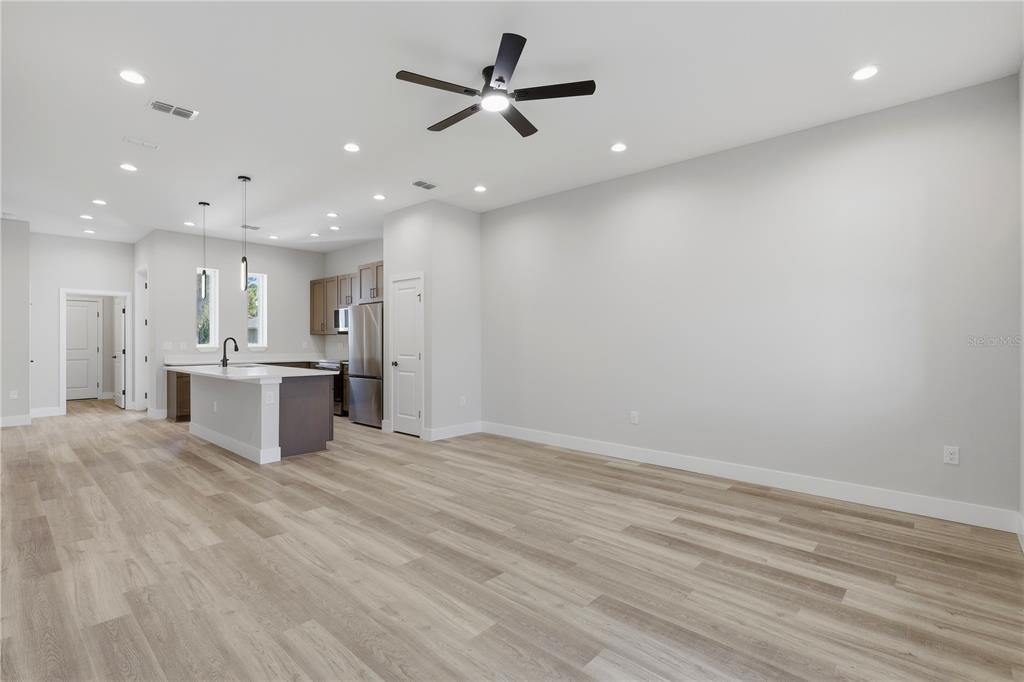 A bright, open-concept living area features light wood-look flooring, a ceiling fan, and a kitchen — 6 UNICORN COURT UNIT A & B, PALM COAST, FL