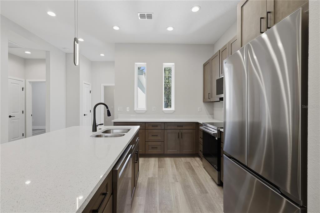 A modern kitchen features dark wood cabinets, white quartz countertops, and stainless steel appliances — 6 UNICORN COURT UNIT A & B, PALM COAST, FL