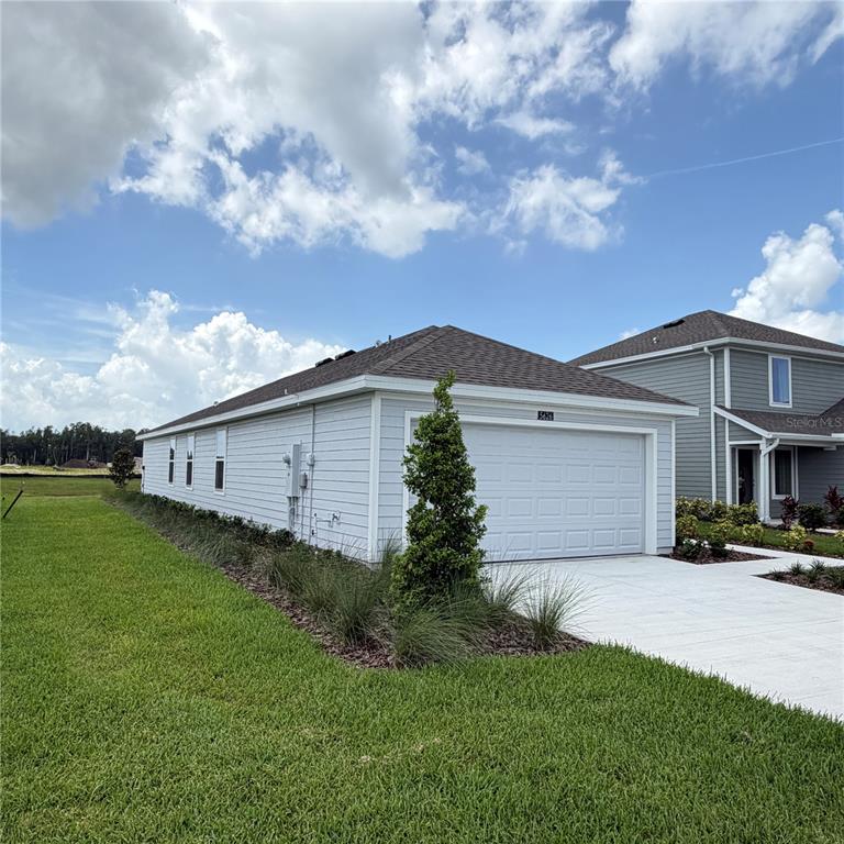 A single-story house with light siding, a two-car garage, and a landscaped front yard — 5626 MORANT BAY PATH, KISSIMMEE, FL