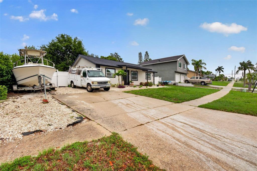 A single-story house with a white boat and a utility van parked in the driveway — 1435 BURNING TREE ROAD, TARPON SPRINGS, FL