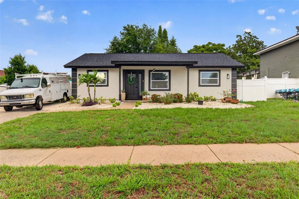 A single-story house with a light-colored exterior, black trim, and a white work van parked — 1435 BURNING TREE ROAD, TARPON SPRINGS, FL