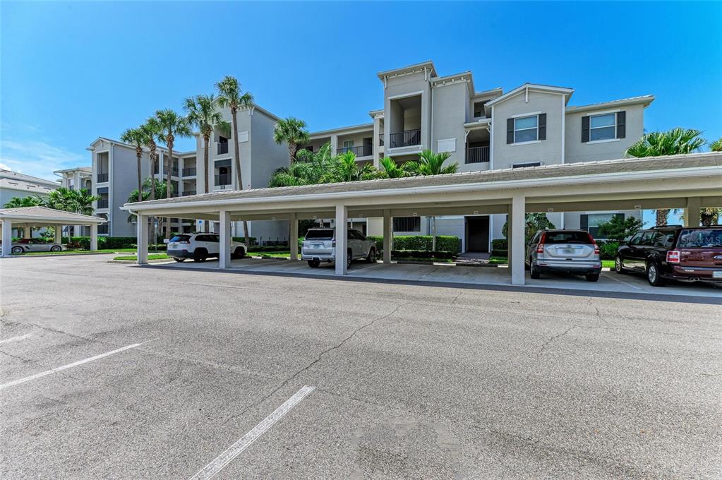 A multi-story apartment building with a covered parking structure in the foreground — 1010 TIDEWATER SHORES LOOP UNIT 304, BRADENTON, FL