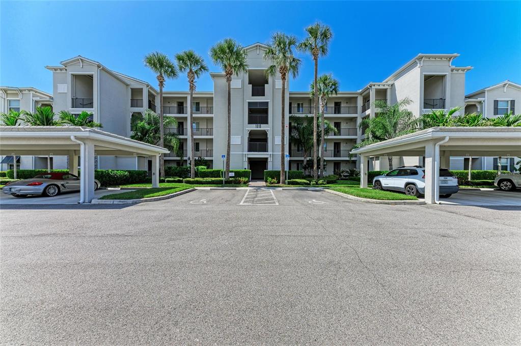 A multi-story apartment building with covered parking spaces in the foreground — 1010 TIDEWATER SHORES LOOP UNIT 304, BRADENTON, FL