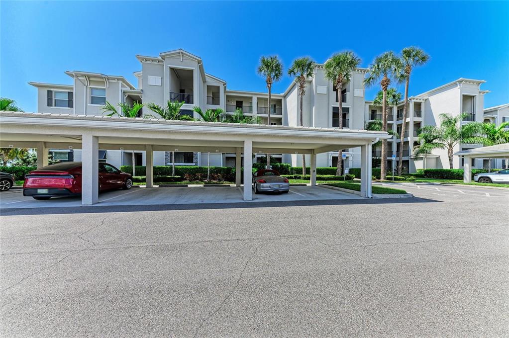 A multi-story apartment building features a covered parking structure in the foreground — 1010 TIDEWATER SHORES LOOP UNIT 304, BRADENTON, FL
