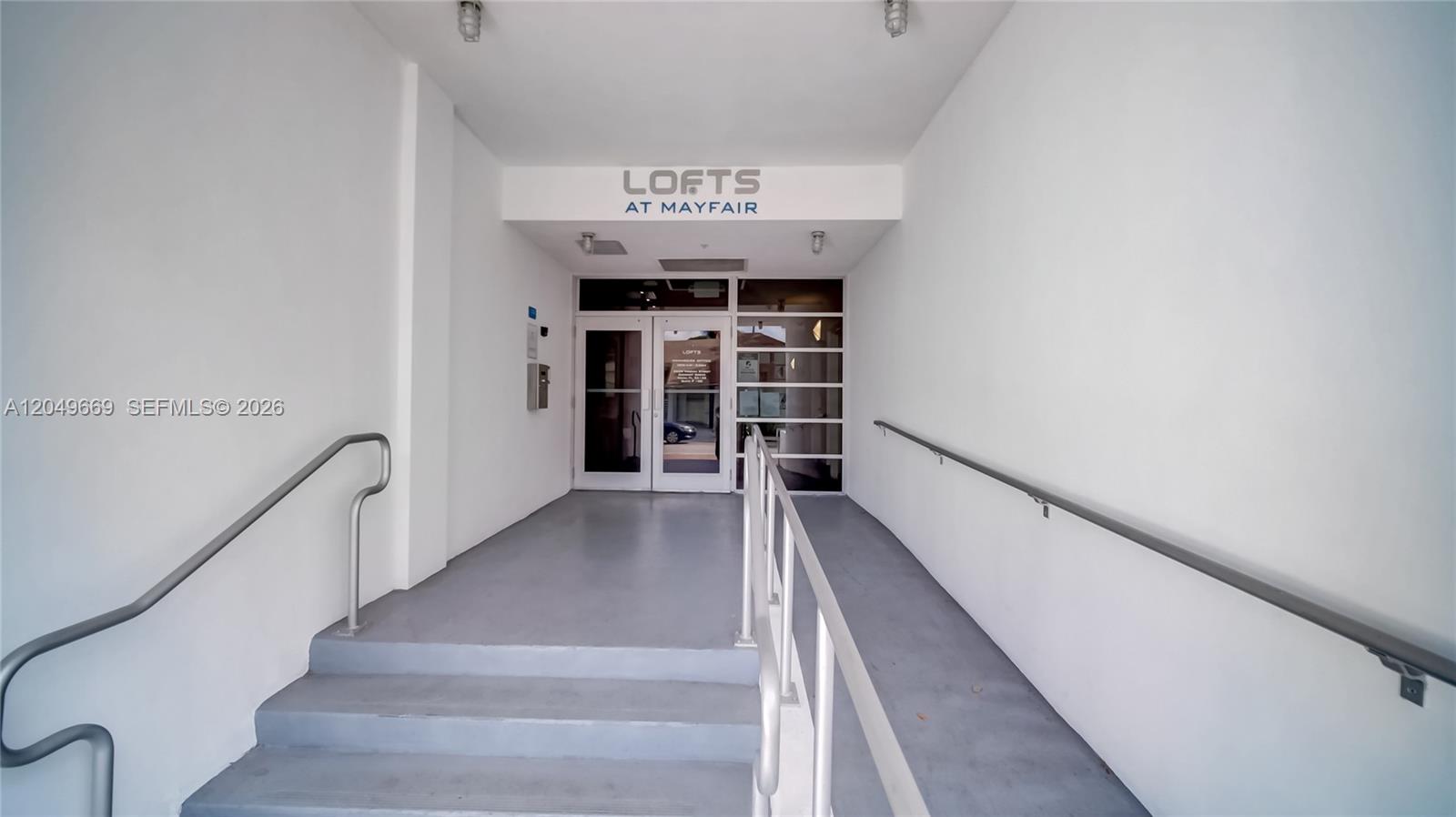 A concrete entryway features a set of stairs and a ramp leading to glass doors — 3339 Virginia St # 323, Miami FL 33133, MIAMI, FL