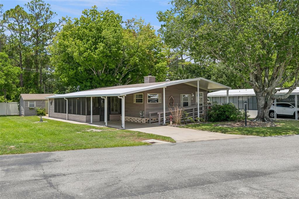 A single-story mobile home with a screened porch, a wheelchair ramp, and a concrete driveway — 938 BLUE HERON BOULEVARD, OSTEEN, FL