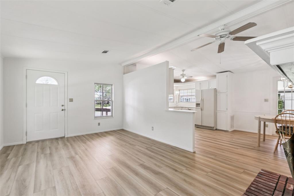 An open-concept living area features light wood-look flooring, white walls, and a partial wall — 938 BLUE HERON BOULEVARD, OSTEEN, FL