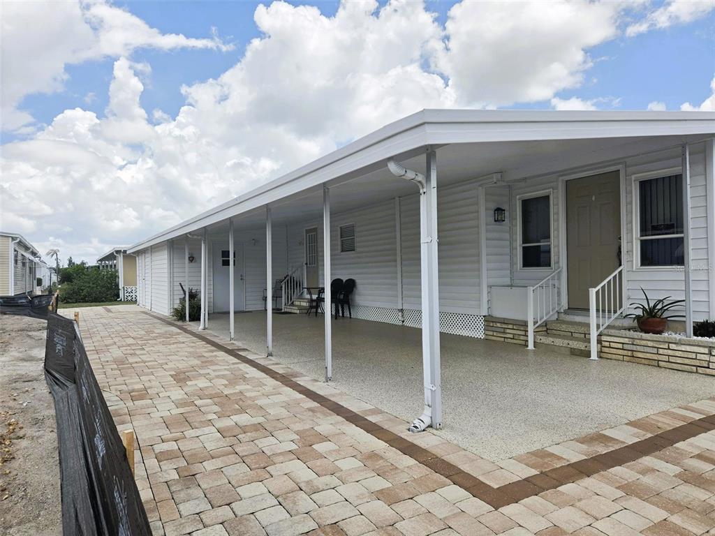 A white mobile home features a long covered carport and a paved brick driveway — 3221 SUMAC TERRACE, SARASOTA, FL