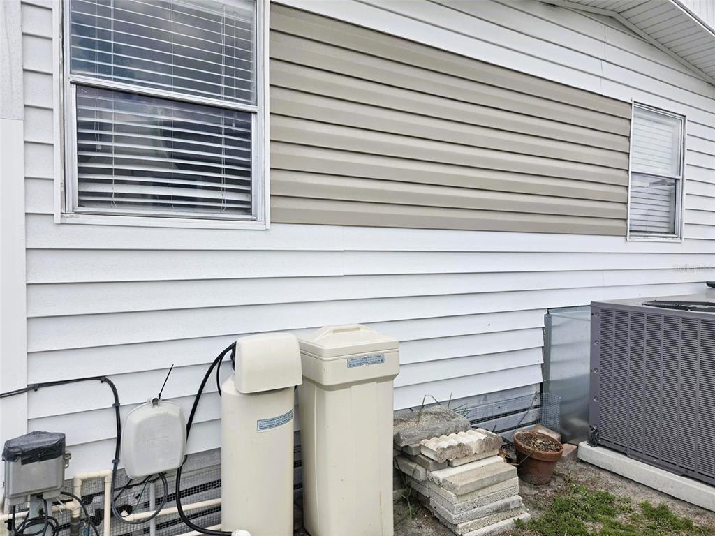 The exterior of a house shows white siding, a tan accent section, and utility equipment — 3221 SUMAC TERRACE, SARASOTA, FL