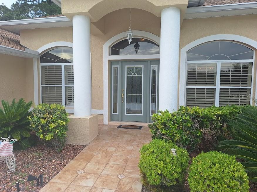 The front entrance features a tiled walkway, two white columns, and a sage green door — 39 EVANS DRIVE, PALM COAST, FL
