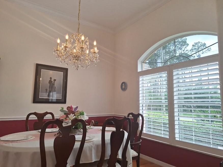 A dining room features a crystal chandelier, white plantation shutters, and a dark wood table — 39 EVANS DRIVE, PALM COAST, FL