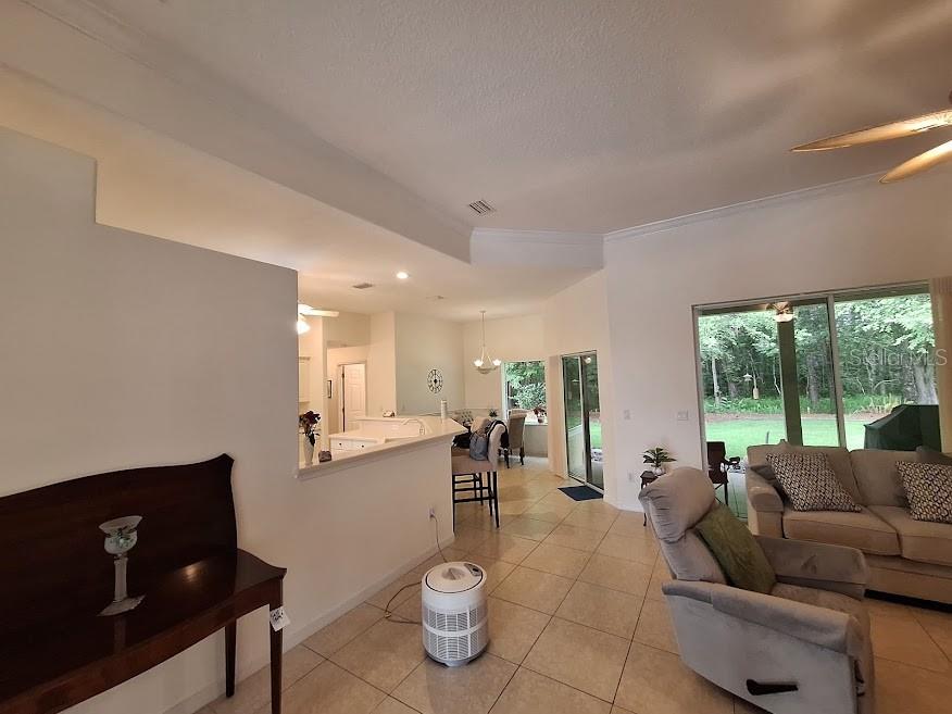A living room with tile floors opens to a kitchen and a view of trees — 39 EVANS DRIVE, PALM COAST, FL