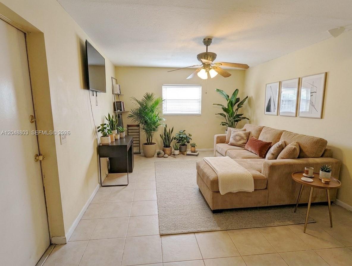 A living room features a tan sectional sofa, tiled floors, a ceiling fan, and plants — 1829 N A St # 50, Lake Worth FL 33460, LAKE WORTH, FL