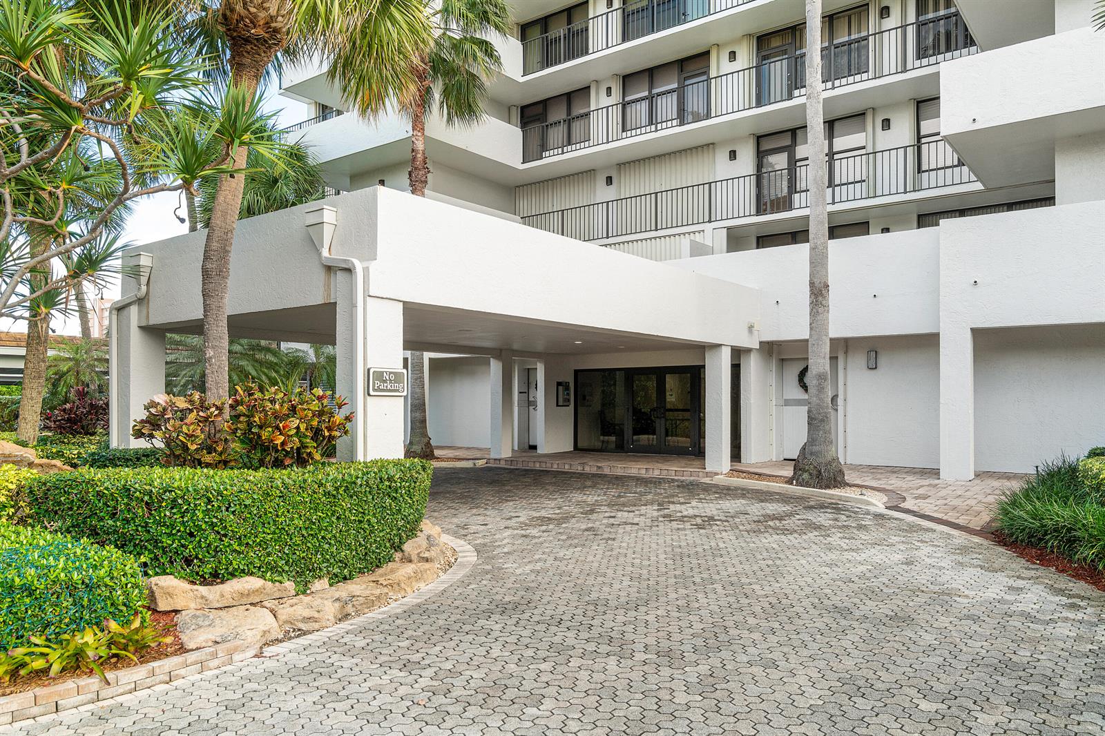 A paved driveway leads to the covered entrance of a multi-story white apartment building — 4600 S Ocean Boulevard # 602, Highland Beach FL 33487, HIGHLAND BEACH, FL