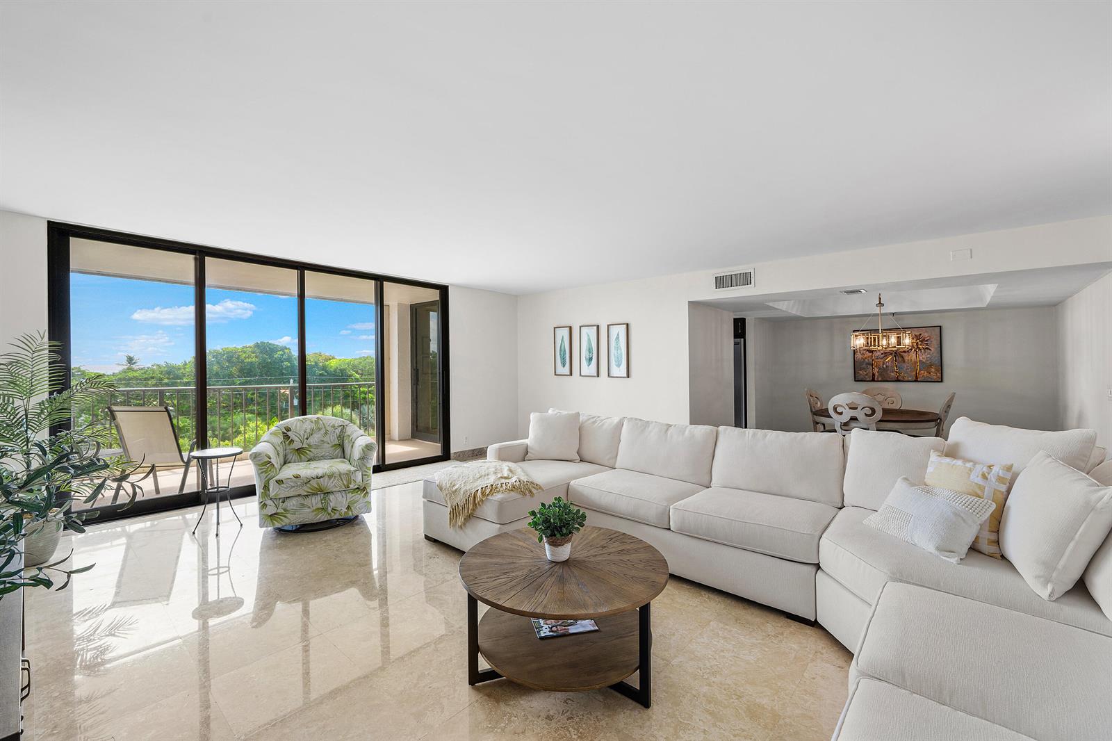 A bright living room features a large white sectional, a round wooden table, and balcony access — 4600 S Ocean Boulevard # 602, Highland Beach FL 33487, HIGHLAND BEACH, FL