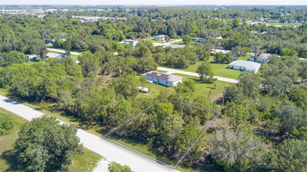 An aerial view shows a vacant, wooded lot outlined in white next to a residential house — 11356 4TH AVENUE, PUNTA GORDA, FL