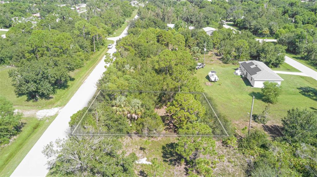 An aerial view shows a rectangular, wooded vacant lot bordered by a road and grass — 11356 4TH AVENUE, PUNTA GORDA, FL