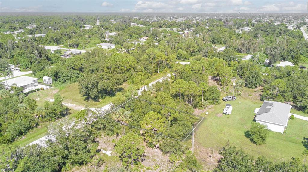 An aerial view shows a rectangular vacant lot outlined in white amidst a wooded residential area — 11356 4TH AVENUE, PUNTA GORDA, FL