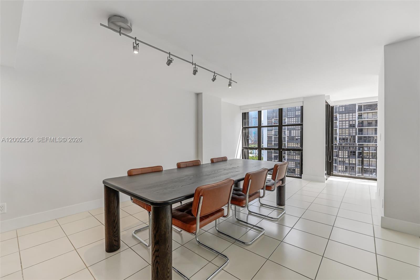 A dining room features a dark wood table, leather chairs, tile flooring, and track lighting — 1915 Brickell Ave # C1404, Miami FL 33129, MIAMI, FL