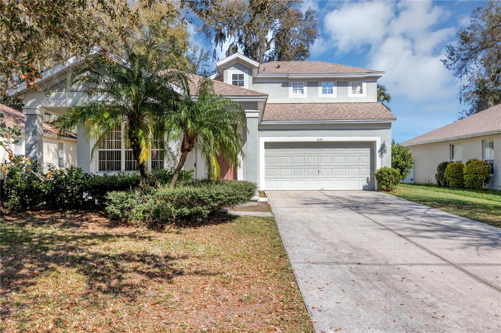 A two-story suburban house with a gray stucco exterior, a two-car garage, and a palm tree — 2193 GRANGER AVENUE, KISSIMMEE, FL