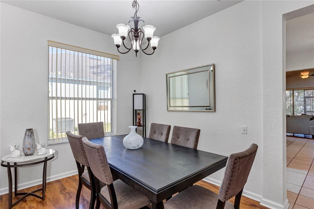 A dining room features a dark wood table, upholstered chairs, a chandelier, and a wall mirror — 2193 GRANGER AVENUE, KISSIMMEE, FL