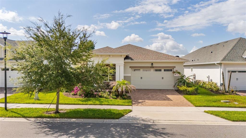 A single-story house with a two-car garage, a paved driveway, and a front yard tree — 2733 SOUTHLAND STREET, ST CLOUD, FL