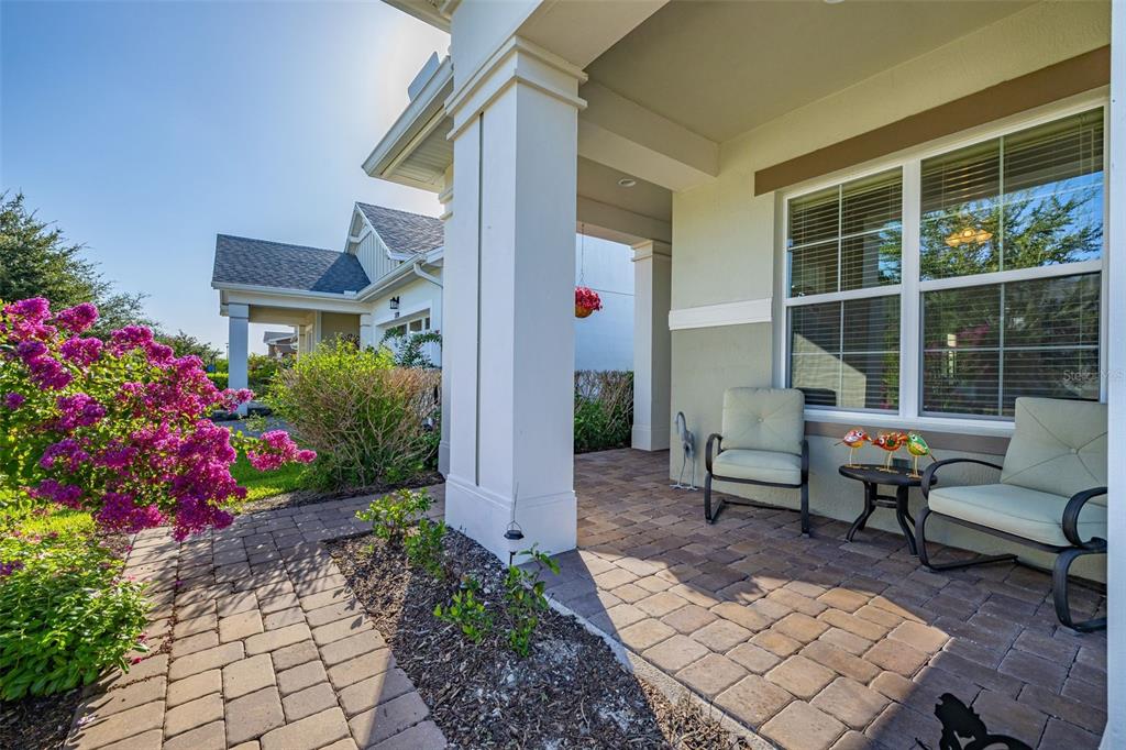 A paved front porch features two chairs, a small table, and a vibrant pink flowering bush — 2733 SOUTHLAND STREET, ST CLOUD, FL