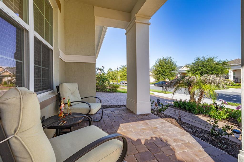 A covered front porch features two cushioned chairs, a small table, and paver flooring — 2733 SOUTHLAND STREET, ST CLOUD, FL
