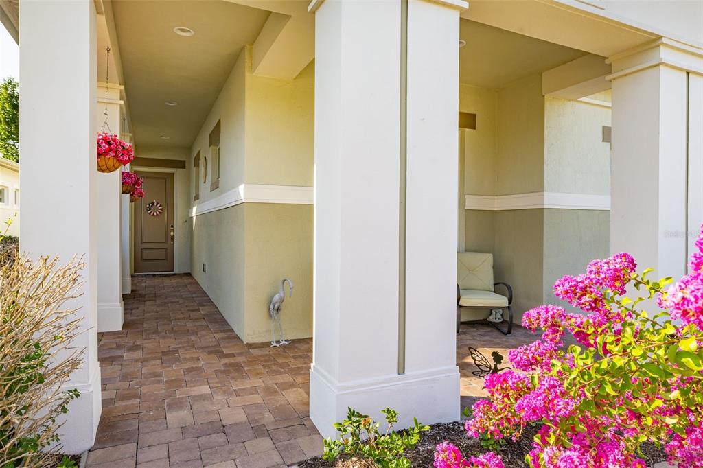 A covered front porch features a paver floor, white columns, and pink flowering bushes — 2733 SOUTHLAND STREET, ST CLOUD, FL