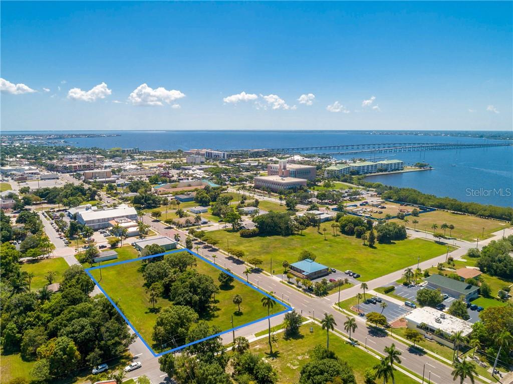An aerial view shows a vacant, tree-filled rectangular lot outlined in blue near a waterfront — 427,407, 417, 425 E OLYMPIA AVENUE, PUNTA GORDA, FL